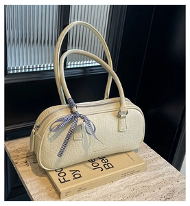 Detail of cream Boston bag with cracked leather texture and blue checkered ribbon bow