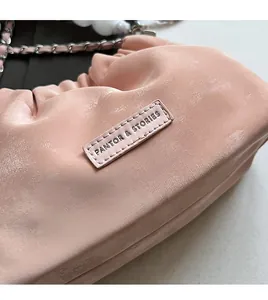 Detail view of pink pleated bucket bag showing the brand tag and metal chain strap