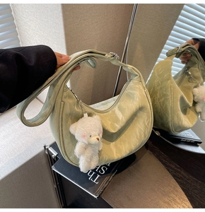 Primer plano de bolso hobo verde menta plisado con un adorno de oso de peluche