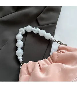 Detail of pink ruched cloud bag with white marble-textured bead handle and metal clasp