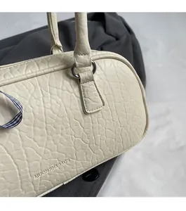 Close-up of reinforced strap buckle and pebbled leather texture on beige shoulder bag