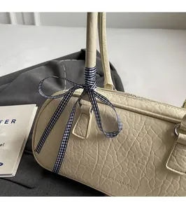 Close-up of cream leather shoulder bag with lychee texture and blue checkered scarf detail