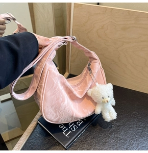 Detalle de bolso bandolera plisado rosa textura terciopelo con oso blanco colgante