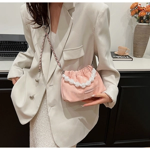 Detailed shot of a pink velvet pleated bucket bag with pearl handle and chain strap