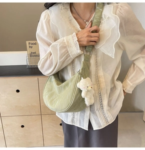 Detalle del bolso de media luna verde claro con textura de mármol y colgante suave