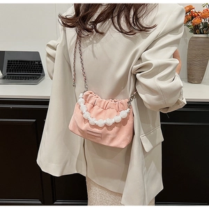 Detailed side view of a pink cloud bucket bag featuring large white pearl handle and chain strap