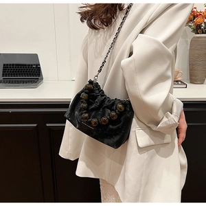 Detail of black pleated bucket bag with amber beads and chic metal chain strap