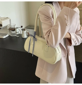 Detail of off-white embossed leather shoulder bag with a blue checkered ribbon decoration