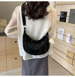 Detalle de bolso de hombro de media luna en terciopelo negro con charm de oso de peluche