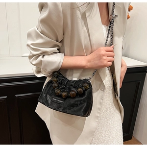 Detail of black velvet bucket bag with brown bead trim and silver chain strap