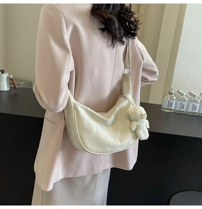 Detalle del bolso hobo blanco roto con textura de mármol y colgante de oso de peluche