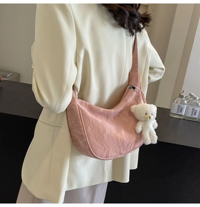 Detalle de bolso rosa con textura plisada y un adorable colgante de oso de peluche blanco