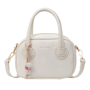 Sac à main en cuir blanc avec bandoulière et perles décoratives sur fond blanc impeccable