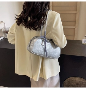 Close-up of textured silver shoulder bag with plaid ribbon handle and metal zipper detail