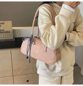 Detail of pink cylindrical shoulder bag with pleated texture and blue checkered ribbon bow