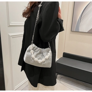 Detail of silver velvet pleated bucket bag featuring oversized pearl handle and silver chain