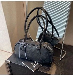 Detail of black textured leather cylindrical bag with stylish blue and white bow decor
