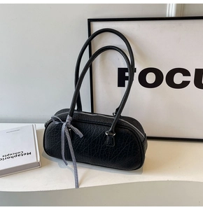Detailed view of the black embossed leather underarm bag with a checkered ribbon accent