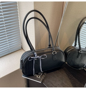Detail of black faux leather bowling bag with crocodile texture and blue plaid bow
