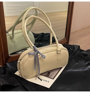 Detail of beige crocodile embossed handbag with bow accessory on black silk