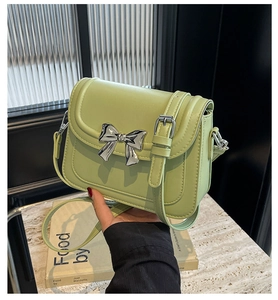 Detail van avocado groene crossbody tas met zilveren metalen strik en riem