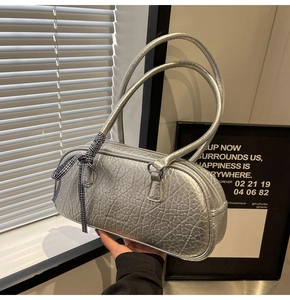 Detail of silver metallic Boston bag featuring pleated texture and plaid ribbon bow