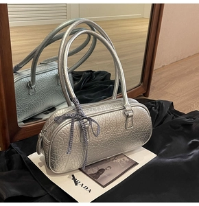 Silver crackle leather handbag with bow ribbon detail on black satin background
