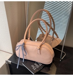 Pink marble texture handbag with ribbon bow detail and long strap on a mirror surface