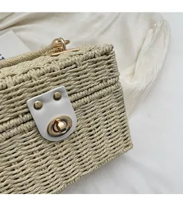 Close-up of beige woven straw bag featuring a golden circular metal lock and leather detail