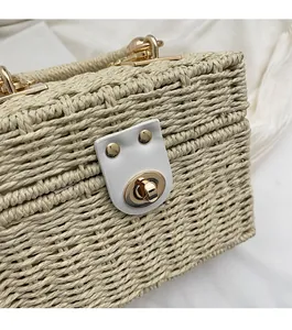 Close-up of golden twist lock and white leather trim on woven straw shoulder bag