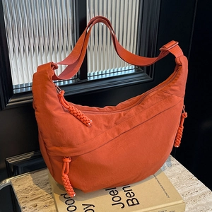 Orange nylon half-moon crossbody bag with woven zipper pulls and adjustable strap