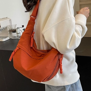 Caramel nylon crescent crossbody bag with woven zipper pulls and adjustable strap