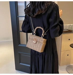 Detail of woven straw bag with metallic chain strap and round buckle on black dress
