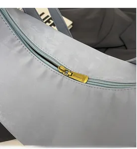 Gros plan d'une fermeture éclair dorée avec logo sur un sac fourre-tout gris-bleu