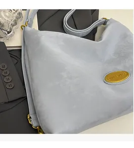 Gros plan d'un sac à bandoulière bleu clair mat avec boucles dorées et sangle réglable