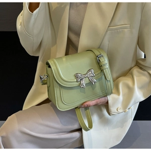 Detailopname lichtgroene crossbody tas met zilveren strik gedragen door model