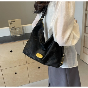 Détail du grand sac cabas noir avec texture vintage et plaque de logo dorée ovale