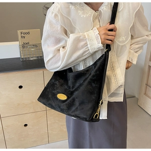 Détail de la texture en daim doux et de la plaque dorée sur le sac hobo noir
