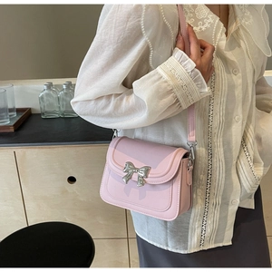 Detail van roze lederen crossbodytas met zilveren strikgesp gedragen op de schouder