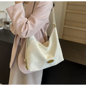Détail du sac cabas crème avec plaque en métal doré et texture mate de qualité premium