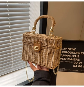 Macro detail of hand-woven straw box bag with leather buckle and gold metal hardware