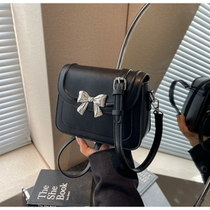 Detailopname van zwarte crossbody tas met zilveren strik en verstelbare schouderband
