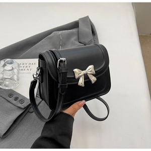 Detail van de zwarte vierkante crossbodytas met zilveren strik en klepsluiting