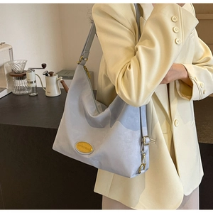 Détail de la bandoulière réglable et du logo doré sur un sac fourre-tout en nylon bleu