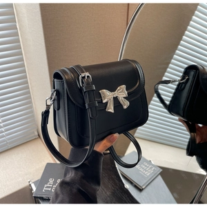 Detail van zwarte leren crossbodytas met een decoratieve zilveren metalen striksluiting