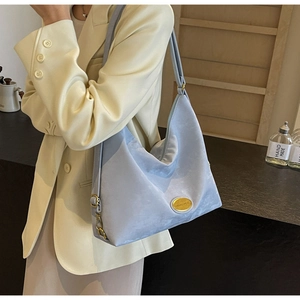 Détail du sac hobo en daim bleu clair avec emblème doré et boucle métallique