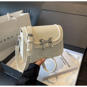 Detailweergave van de crèmekleurige PU-leren handtas met een zilveren metalen striksluiting