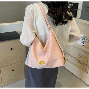 Détail du sac cabas rose avec logo en métal doré porté par un mannequin en intérieur