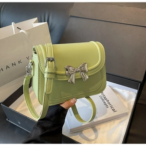 Detail van lichtgroene PU-leren crossbodytas met een zilveren metalen striksluiting