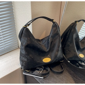 Gros plan d'un sac hobo noir vintage avec texture cuir vieilli et plaque dorée